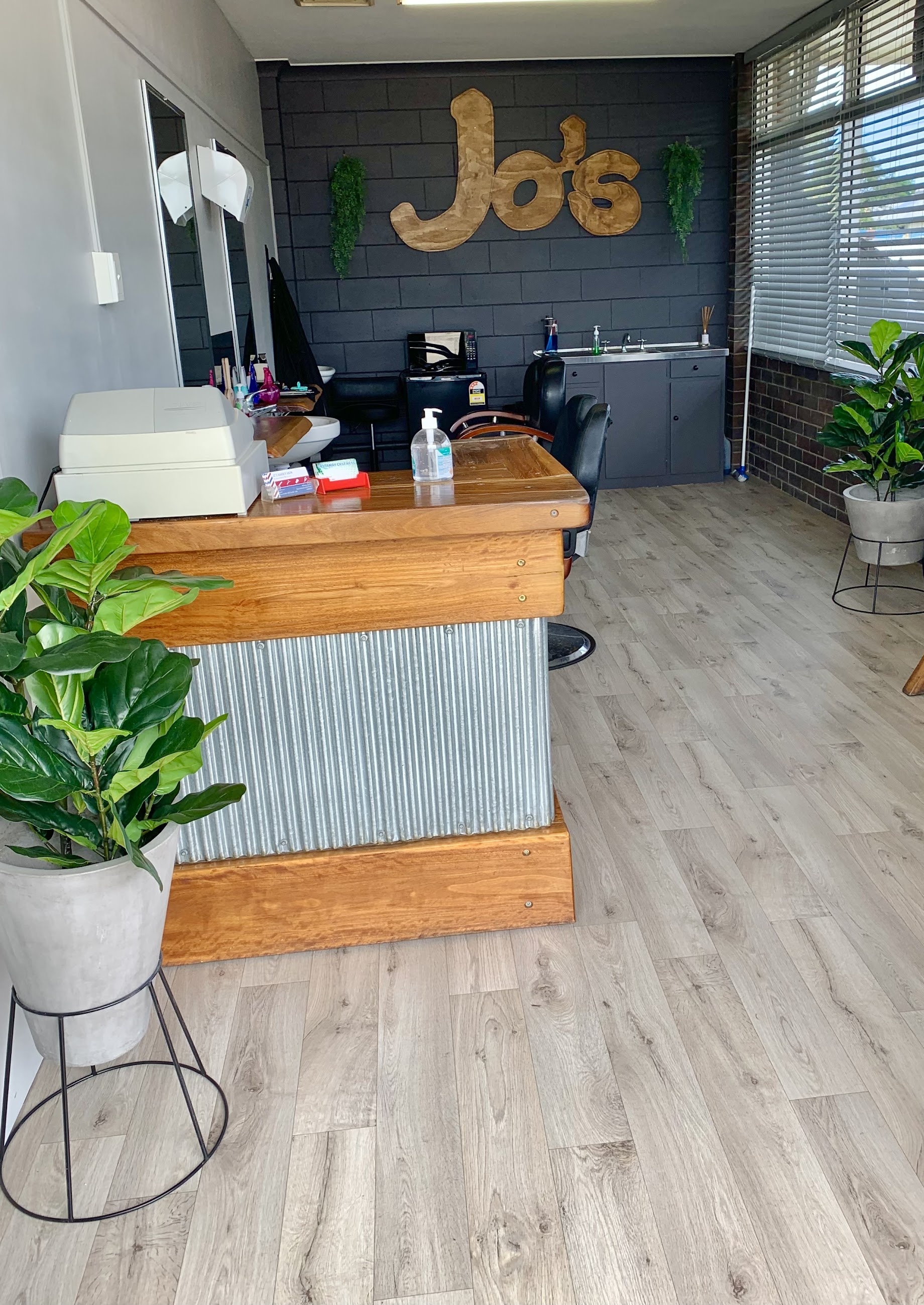 Inside Jo's Barber Barn: the timber and corrugated iron counter, the barber chair and the Jo's sign on the dark brick wall