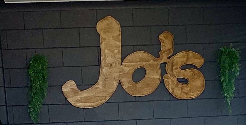 The timber Jo's sign on the shop's dark brick feature wall